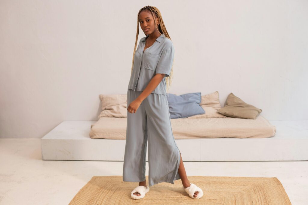Young woman posing in comfortable loungewear with fluffy slippers in a minimalist setting.
