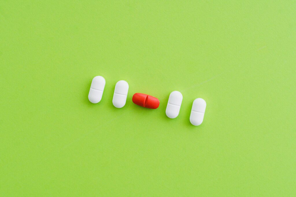 Close-up of colorful pills arranged on a bright green surface representing healthcare.